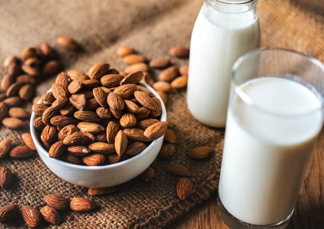 Clear Glass With Milk Beside the Bowl Full With Almonds