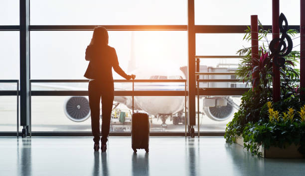 Silhouette of business traveler makes a call while waiting for her flight Silhouette of business traveler makes a call while waiting for her flight. business class flight stock pictures, royalty-free photos & images