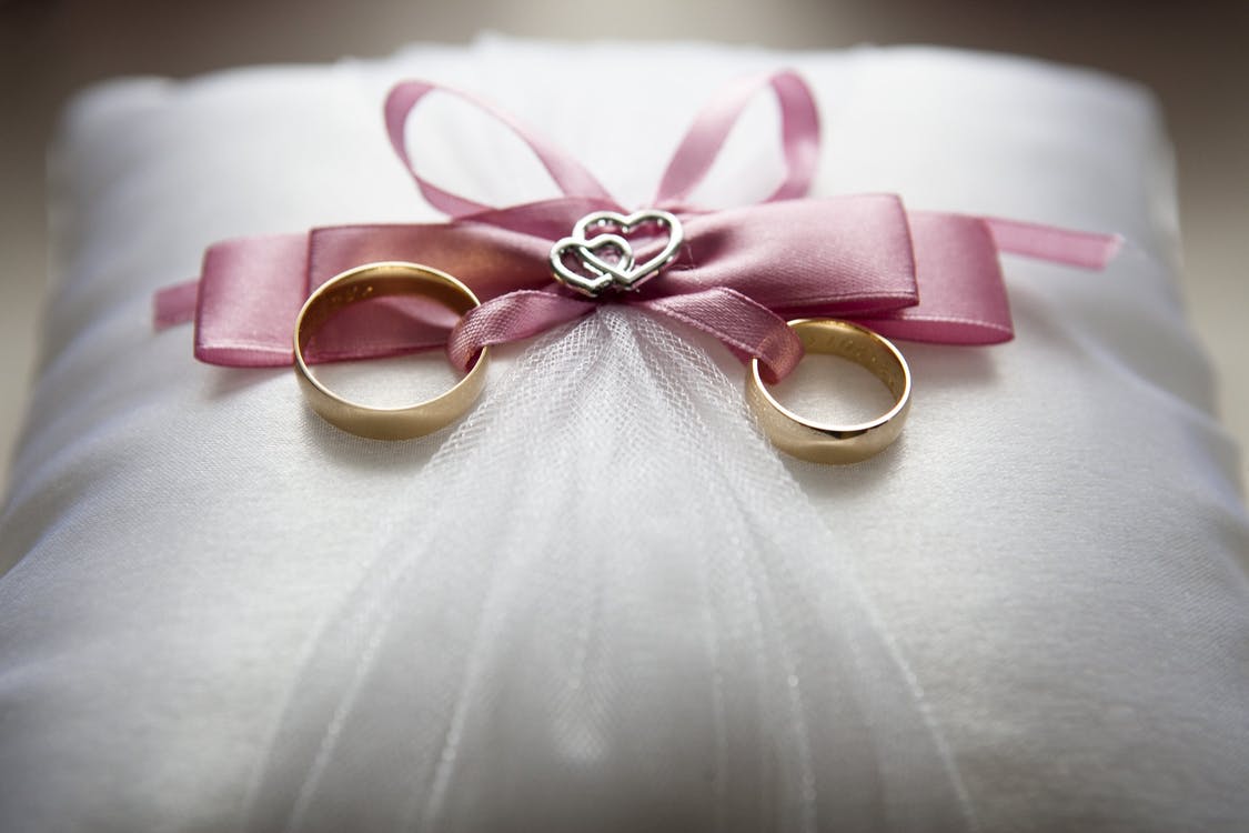 Free Selective Focus Photography of Silver-colored Engagement Ring Set With Pink Bow Accent on Throw Pillow Stock Photo