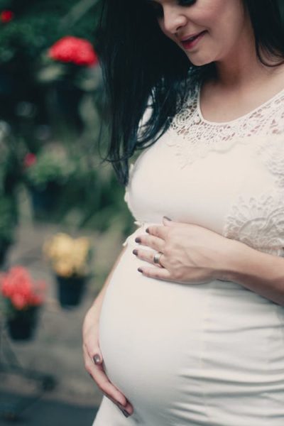Close-up Photo of Pregnant Woman In White Dress Holding Her Stomach